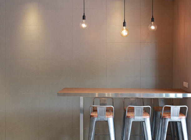istock Modern table counter bar with chairs loft interior with gray tile wall and hanging decor lamps. 1059454448