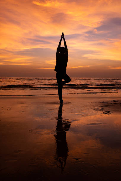 istock Silhouette of a young man meditating at sunset 1059461908