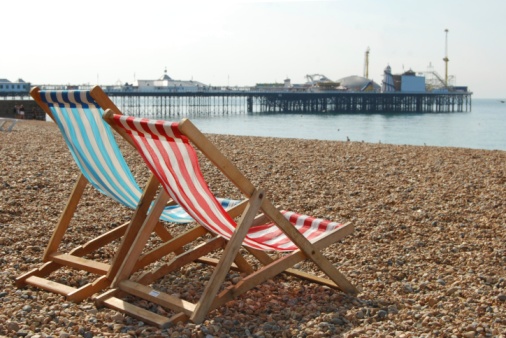 Two empty deckchairs on Brighton beach (England) with pier in the background
