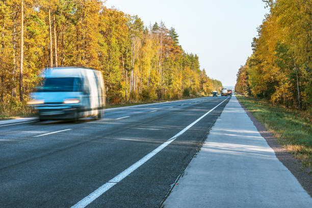 秋には、森林、自然。木の枝を太陽光線を持つカラフルなフォレストのキエフ-ワルシャワを高速道路で明るい朝。太陽の光と自然の風景。 - country road trucking car yellow ストックフォトと画像