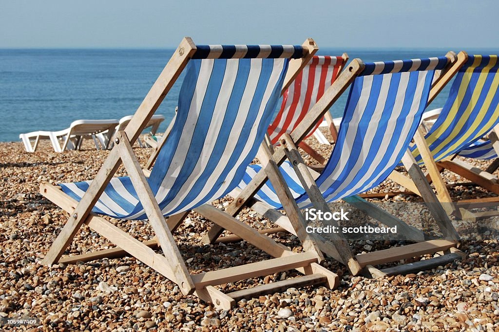 Deckchairs on beach Many colorful deckchairs on a pebble beach at Brighton, England Beach Stock Photo