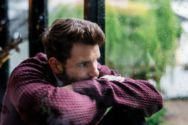 hombre pensativo mirando por la ventana - beautiful staring caucasian one person fotografías e imágenes de stock