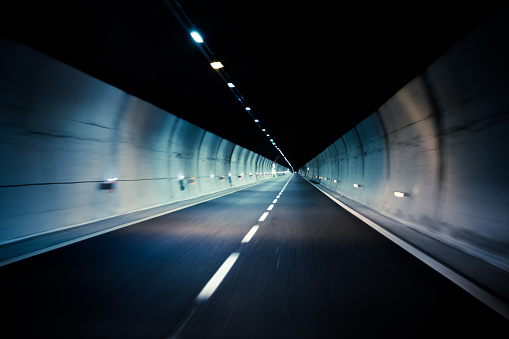 car driving through dark modern city tunnel