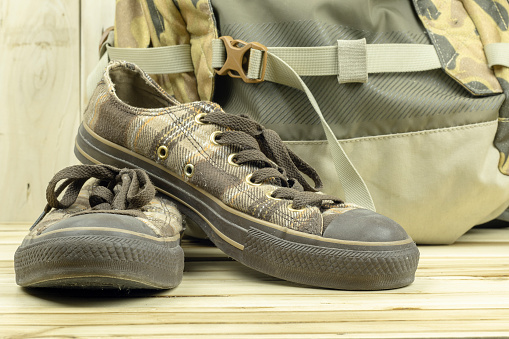 Brown sneakers with backpack on the wooden background.