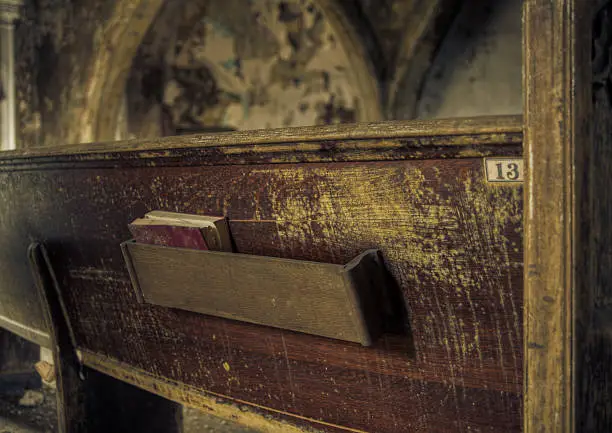 Image of a hymnbook on a church pew in an empty, derelict abandoned church.