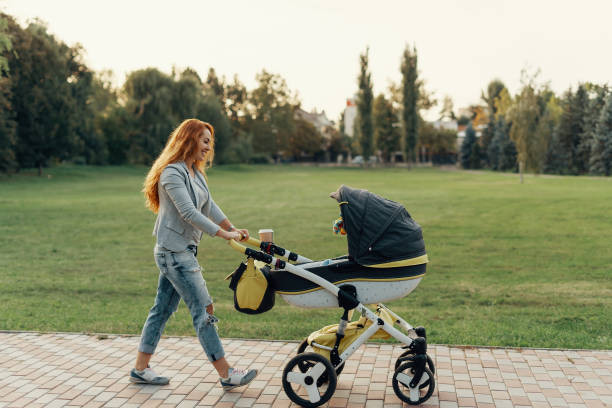 Mother enjoying walk carrying her little child in his baby trolley. stock photo