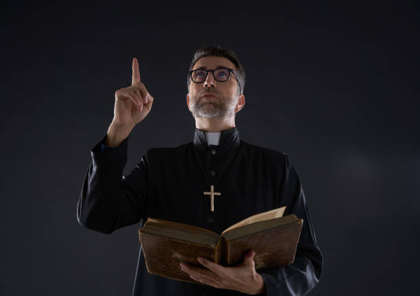 istock Priest holding bible pointing finger up 1059515882