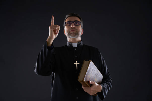 istock Priest holding bible pointing finger up 1059516022