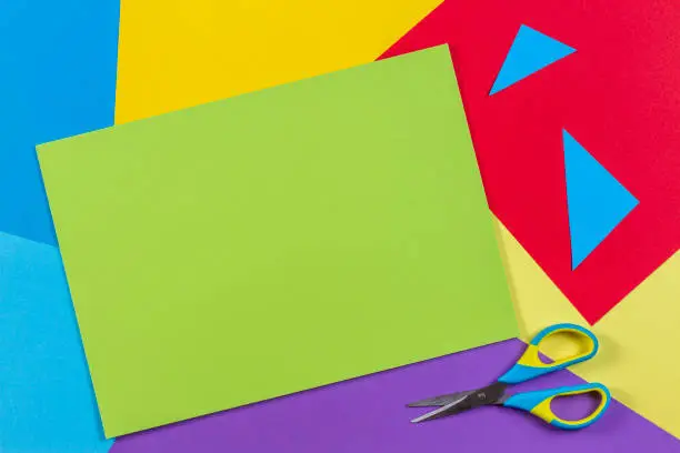 Photo of Top view of colored paper with colorful scissors. Kids art and craft paper applique background