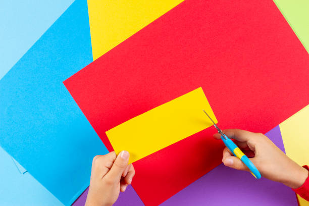 istock Kid's hands cutting colored paper with scissors 1059526950
