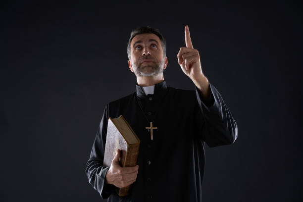 istock Priest holding bible pointing finger up 1059533116