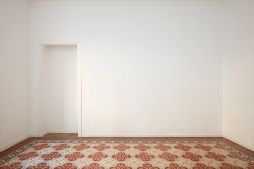 Blank, white wall with niche and decorated tiled floor in a renovated ancient interior