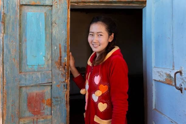 Uzbek girl looking through old doors, in Nukus, Uzbekistan Nukus, Uzbekistan - October 18, 2018: Central asian girl smiles and looks at me through wooden doors, in Nukus, Uzbekistan. bukhara stock pictures, royalty-free photos & images