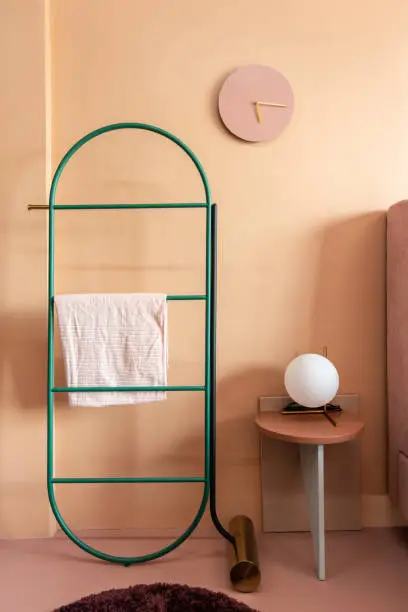 Custom hanging shelve with gold circular table lamp on side table and clock installed on oldrose painted wall / cozy interior concept / nice idea decoration / studio for advertising