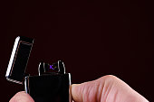 Close up of man using a plasma arc lighter. Windproof, flameless and rechargeable electric lighter