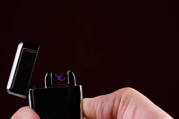 Close up of man using a plasma arc lighter. Windproof, flameless and rechargeable electric lighter Close up of man using a plasma arc lighter. Windproof, flameless and rechargeable electric lighter. Copy space. cigarette lighter stock pictures, royalty-free photos & images