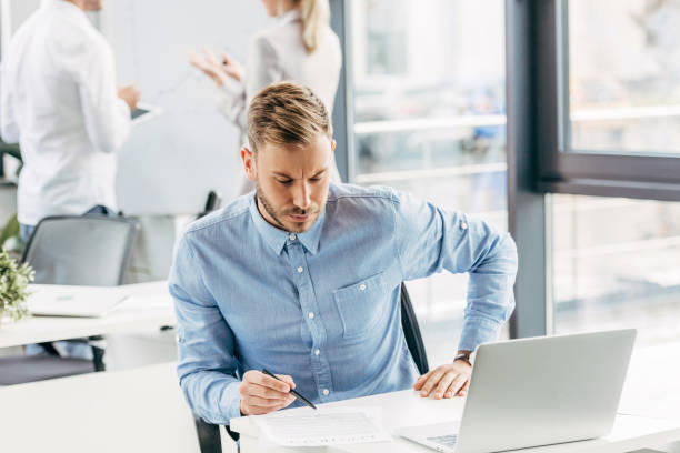 istock handsome young businessman working with laptop and papers in office 1059551310