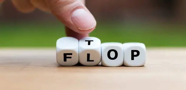 Photo of Hand is turning dice and changes the word Flop to Top