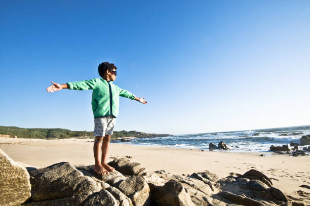 istock Sensing Freedom: Little Boy Posing By The Seaside. Clear Blue Sky Background 1059560480