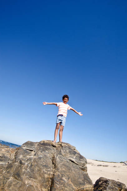 istock Sensing Freedom: Little Boy Posing By The Seaside. Clear Blue Sky Background 1059565108