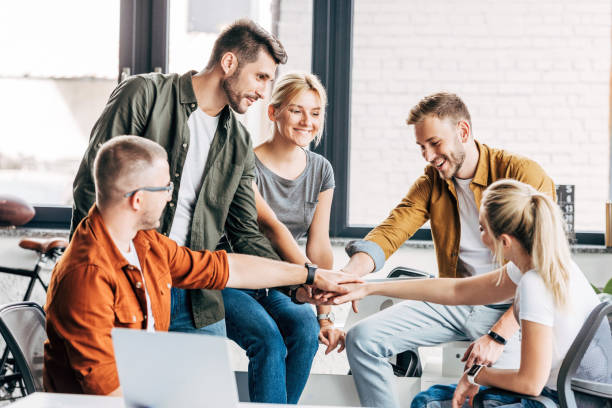 istock group of happy young entrepreneurs making team gesture while working on startup together at office 1059568098