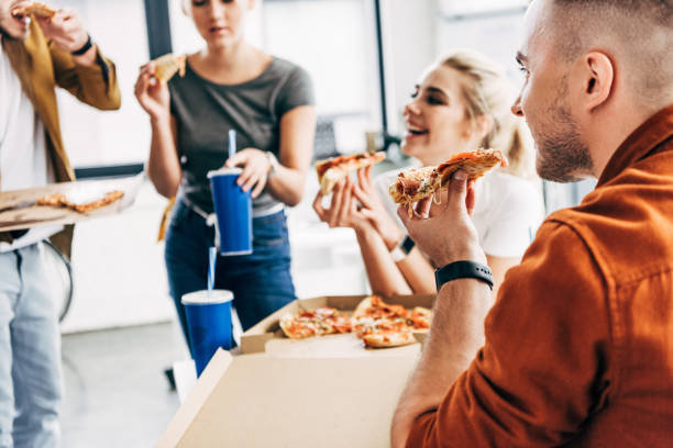istock group of happy entrepreneurs having pizza for lunch together while working on startup at office 1059568928