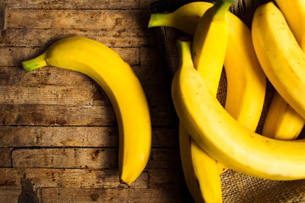 素朴なテーブルにバナナ - banana bunch yellow healthy lifestyle ストックフォトと画像