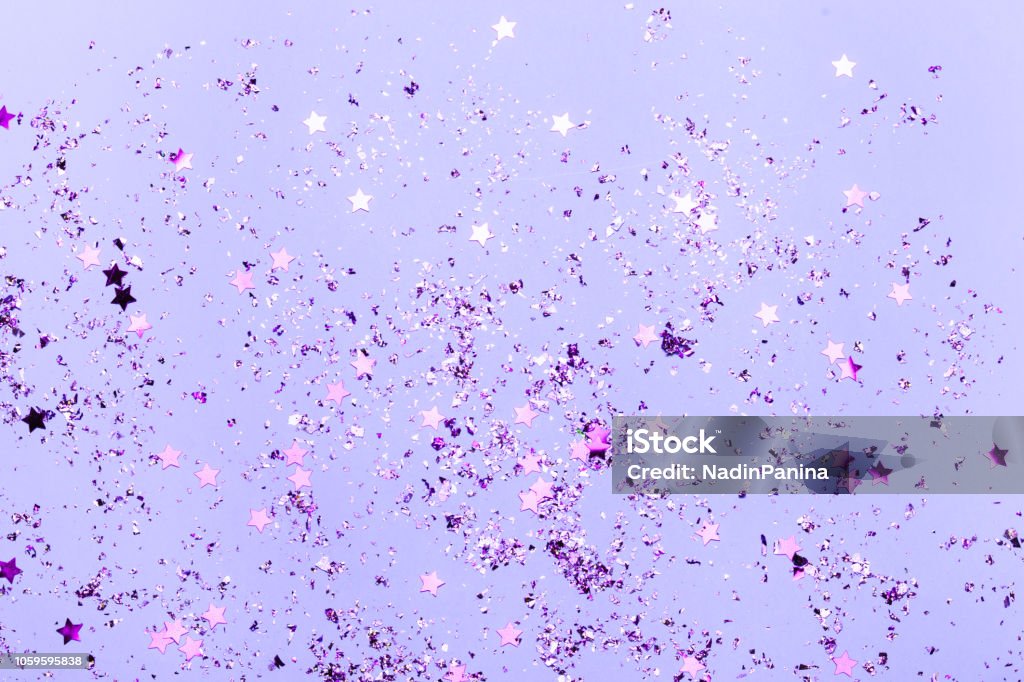 Violet confetti and violet stars and sparkles on violet background. Violet confetti and violet stars and sparkles on violet background. Top view, flat lay. Copyspace for text. Bright and festive holiday background. For Christmas, New year, Mother's day. Purple Stock Photo