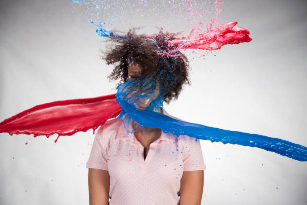Watercolour paints splashing on young woman Watercolour paints splashing on young woman standing against white background. covered in paint stock pictures, royalty-free photos & images