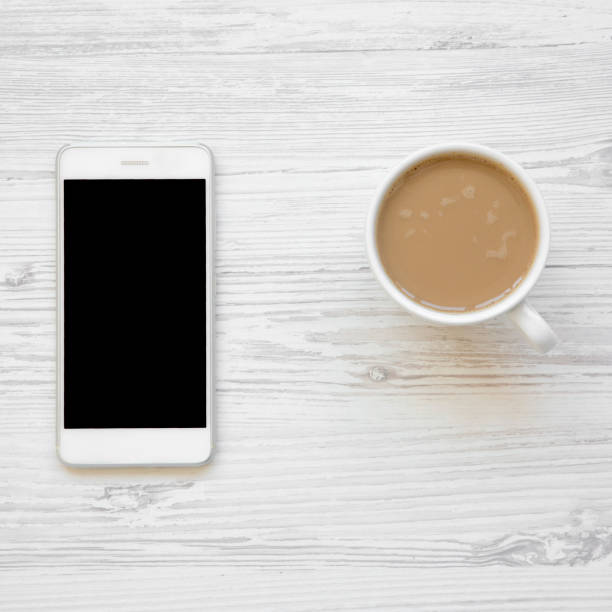 istock Smartphone and latte on white wooden table, overhead view. Flat lay, from above. 1059604362
