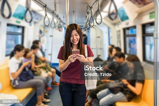 istock Asian woman passenger with casual suit using the smart mobile phone in the Skytrain rails or subway for travel in the big city, lifestyle and transportation concept 1059611154