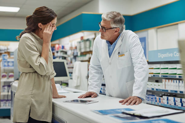 I need something for these headaches Shot of a mature pharmacist helping a customer at the counter in a chemist melancholy computer support specialist stock pictures, royalty-free photos & images