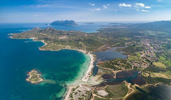 The beautiful bays and beaches of Sardinia, South of the City Olbia with the famous Tavolara Mountain in back. Aerial Panorama. Converted from RAW.