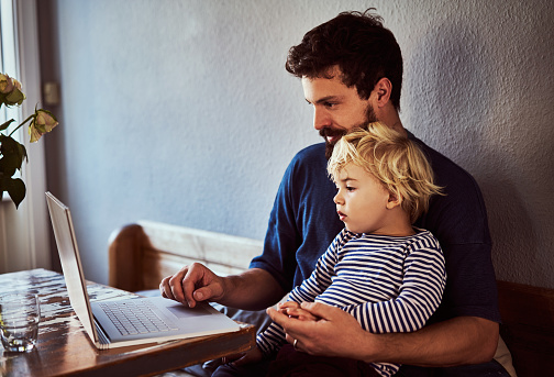 Cropped shot of a young man and his son using a laptop while sitting at the dining room table