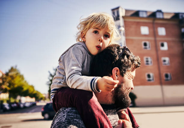 The bond between father and son Cropped shot of a young man piggybacking his adorable little son through the city scandinavian ethnicity stock pictures, royalty-free photos & images