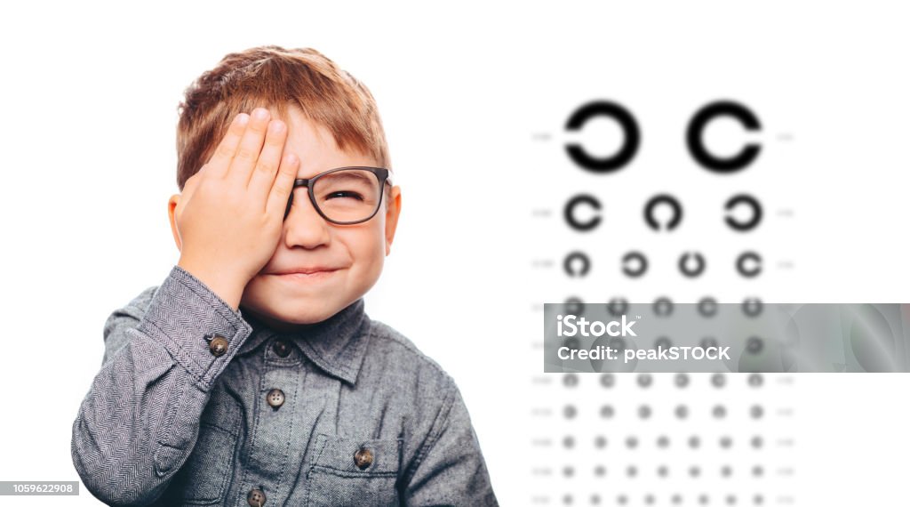 little boy having eye exam with eye chart boy having eye exam with eye chart and covering one eye. Child Stock Photo