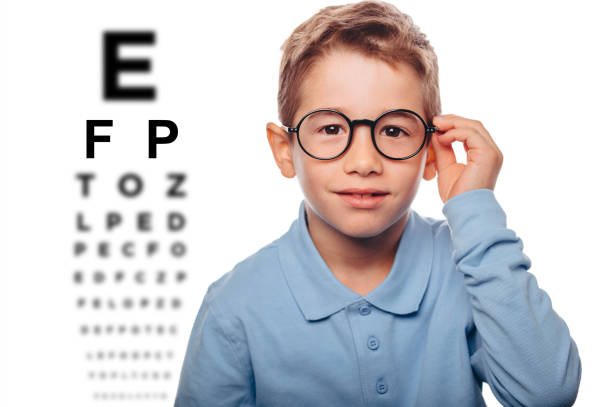 istock little boy wearing glasses standing beside an eye test 1059622936