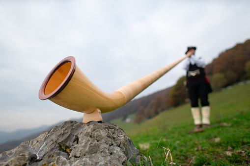 Alpine horn. A man plays in an alpine valley.