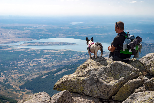 Man with his dog on top of the mountain enjoying the views