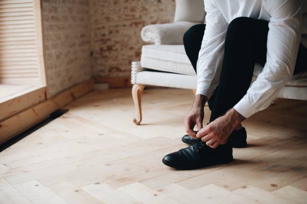 istock Low Section Of Man Tying Shoelace On Sofa At Home 1059629218