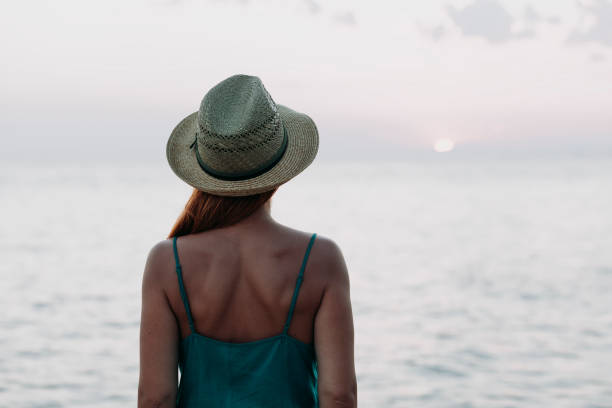 istock Woman watching sunset on the sea horizon 1059629600