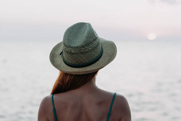 istock Woman watching sunset on the sea horizon 1059629602