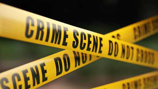 Crime Scene Tape Barrier In Front Of Defocused Background Yellow crime scene do not cross barrier tape in front of defocused background. Horizontal composition with selective focus and copy space. crime scene stock pictures, royalty-free photos & images