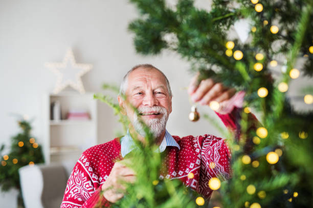 istock A senior man standing by Christmas tree, holding balls ornaments. 1059636890