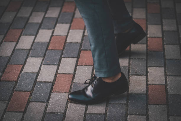 istock Low Section Of Businessman Wearing Shoes While Standing On Footpath 1059637430