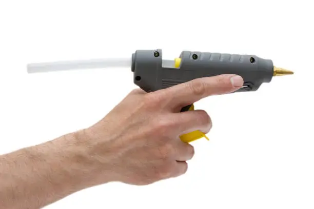Photo of Glue gun in man hand isolated.Handmade using,popular device.