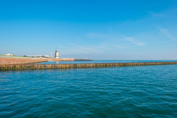 Groyne in sea protecting a coast below a blue sky in sunlight at fall