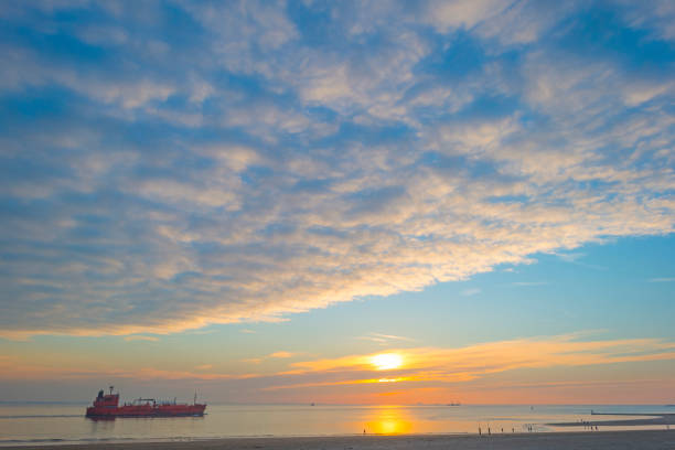 istock Sunset over sea along a beach below a yellow sky at fall 1059643930
