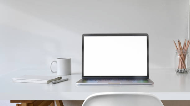 istock Blank white screen laptop with office supplies on white desk workspace. 1059648260