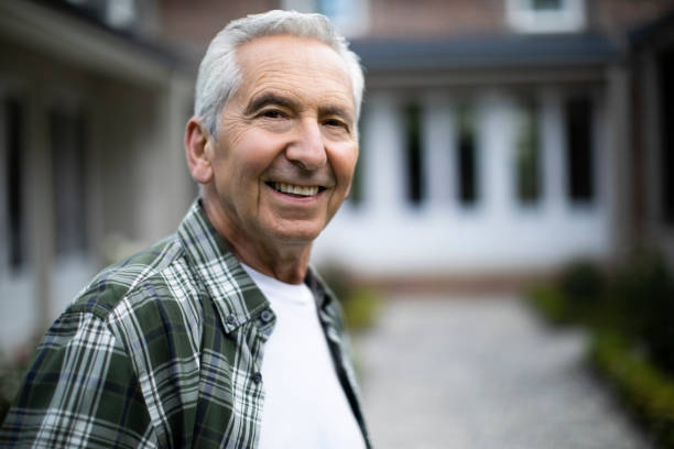 istock Smiling retired senior man standing against house 1059650916